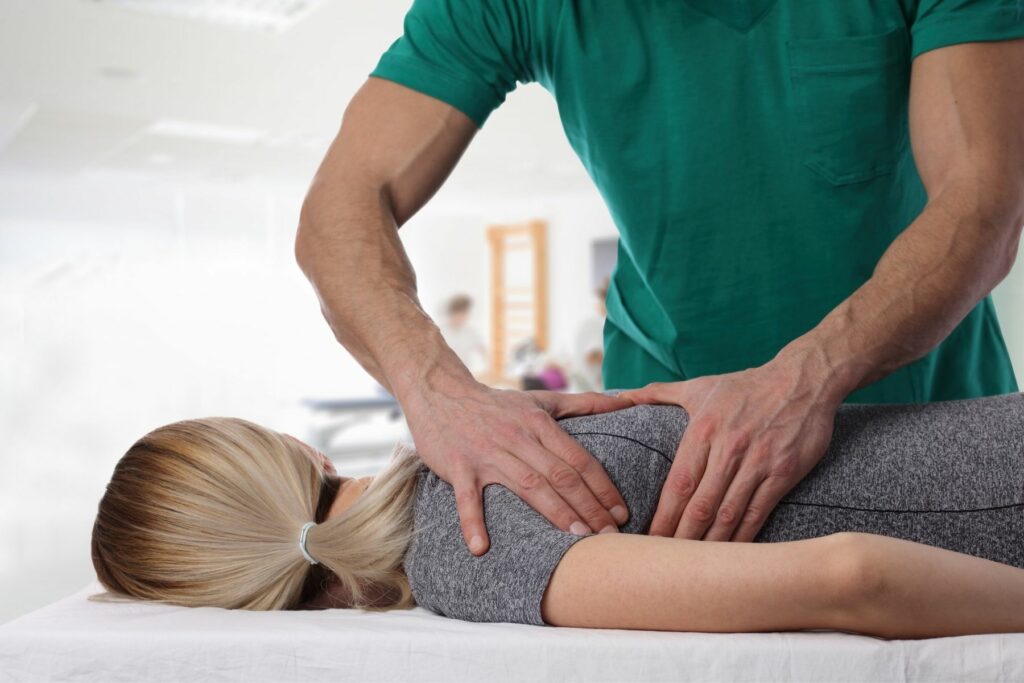 chiropractor in green shirt giving an adjustment to a blond female