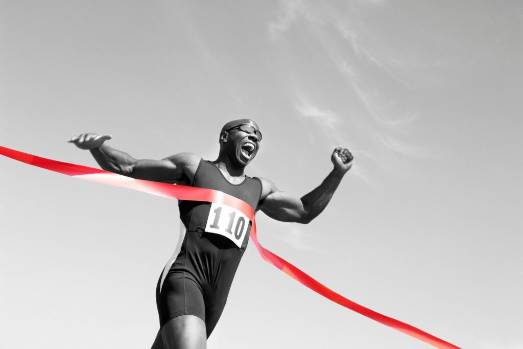 man running through a red ribbon to showcase pain free living with chiropractic care in maryland